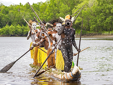 Male paddlers from the village of Uwus perform in a ritualistic greeting ceremony, Asmat Region, Papua, Indonesia.