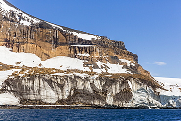 Rust-colored volcanic tuff cliffs above a dark material filled glacier at Brown Bluff, eastern side of the Tabarin Peninsula, Weddell Sea, Antarctica, Polar Regions