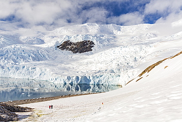 Two hikers surrounded by ice-capped mountains and glaciers in Neko Harbor, Antarctica, Polar Regions