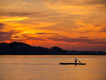 Young man paddling his fishing boat at sunset over calm waters on Clavero Lake, Amazon Basin, Peru, South America