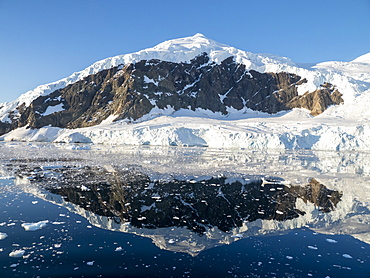 Ice-capped mountains reflected in the calm waters of Neko Harbor, Antarctica, Polar Regions