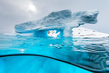 Above and below view of an arch formed in an iceberg at Cuverville Island, Ererra Channel, Antarctica, Polar Regions