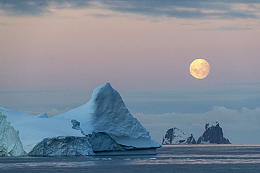 Nearly full moon setting over small islands and icebergs off the Trinity Peninsula, Antarctica, Polar Regions