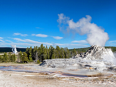 Castle Geyser steaming, with Old Faithful erupting behind, in Yellowstone National Park, UNESCO World Heritage Site, Wyoming, United States of America, North America