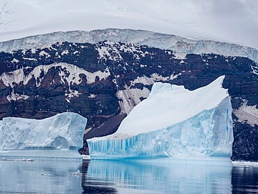 Icebergs surround the glacier covered volcano called Peter I Island in the Bellingshausen Sea, Antarctica, Polar Regions