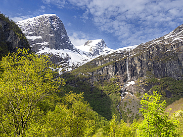 A view of a waterfall on the steep wall of mountains with the Myklebustbreen glacier at the top, Vestland, Norway, Scandinavia, Europe