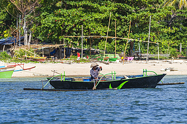 Local fisherman in outrigger boat in the shallow reefs off Bangka Island, off the northeastern tip of Sulawesi, Indonesia, Southeast Asia, Asia