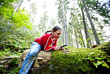 Girl looking at plant through magnifying glass, Styria, Austria