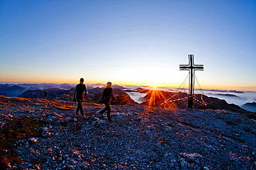 Two hikers at summit of Hochschwab mountain at sunrise, Hochschwab, Styria, Austria