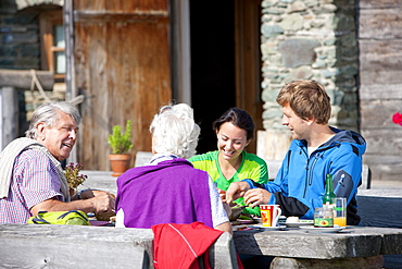 Four hikers having a snack in front of an alpine hut, Styria, Austria