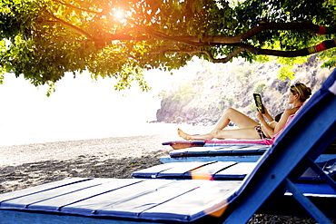 Woman lying on a beach chair while reading, Amed, Bali, Indonesia