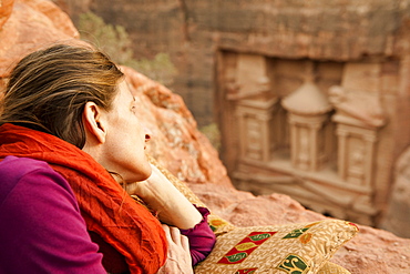 Woman lying on rock, Al Khazneh in background, Petra, Jordan, Middle East