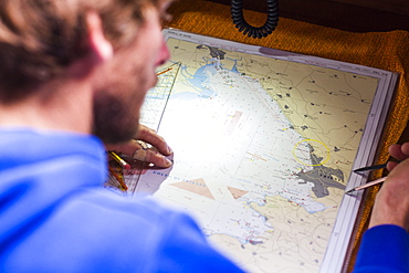 Skipper planing a route on a nautical chart at a sailing boat, Pula, Istria, Croatia