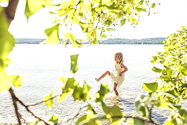 Girl wearing a summerdress standing in lake Starnberg, Berg, Upper Bavaria, Germany