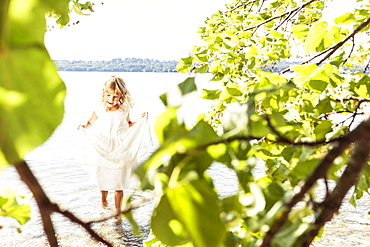 Girl wearing a summerdress standing in lake Starnberg, Berg, Upper Bavaria, Germany