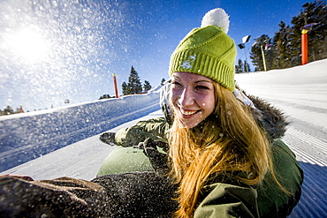 Young woman snow tubing, Kreischberg, Murau, Styria, Austria