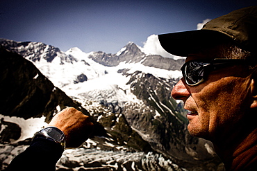 Hiker having a look at a watch, on the way to Schreckhorn hut, Lower Grindelwald glacier, Eiger and Moench in the background, Bernese Oberland, Switzerland