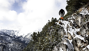 Hiker climbing over snow-covered rocks, ascend to Unnutz Mountain (2078 m), Rofan Mountains, Tyrol, Austria