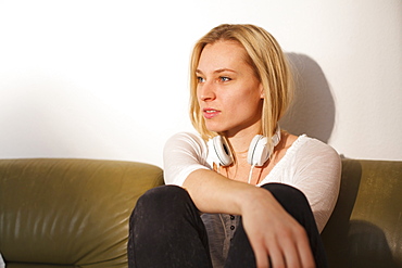 Young woman sitting on the sofa, daydreaming