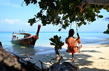 Woman sat on a swing on the beach, Island Kradan, Andaman Sea, south- Thailand, Thailand, Asia