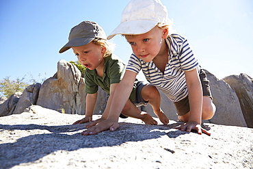 Two boys climbing over rocks, Kubu Island, Makgadikgadi Pans National Park, Botswana