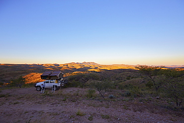 Off-road vehicle with roof top tent in sunrise, Gamsberg pass, Namibia