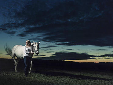 Girl standing next to her horse at dusk, Freising, Bavaria, Germany