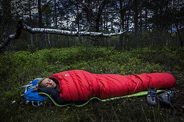 young woman in sleeping bag in a moorland forest, Berg at Lake Starnberg, Upper Bavaria, Germany