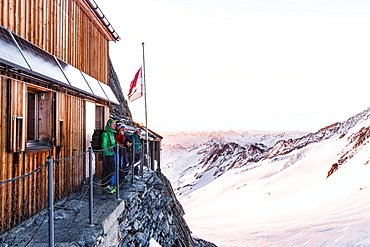 Group standing in front of the Oberaarjoch hut at sunrise, Wallis, Switzerland