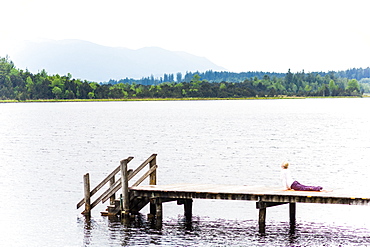 woman is making yoga on the boardwalk, sun salute, Kirchsee, Bad Toelz, Bavaria, Germany