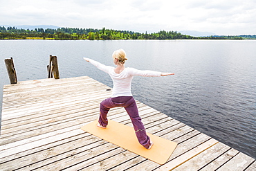 woman doing Yoga on the jetty, sun salute, Kirchsee, Bad Toelz, Bavaria, Germany