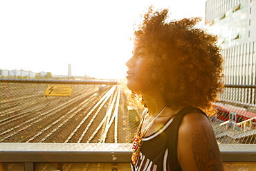 Young afro-american woman in backlight in urban scenery with tracks and station, Hackerbruecke Munich, Bavaria, Germany