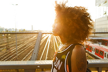 Young afro-american woman in backlight in urban scenery with tracks and station, Hackerbruecke Munich, Bavaria, Germany