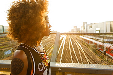 Young afro-american woman in backlight in urban scenery with tracks and station, Hackerbruecke Munich, Bavaria, Germany