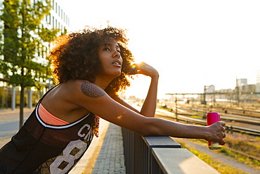 Young afro-american woman relaxed in urban scenery with backlight, Hackerbruecke Munich, Bavaria, Germany