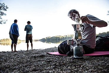 Young man making coffee with a camp cooker, Freilassing, Bavaria, Germany