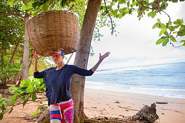 Young woman trying to carry a big basket on her head, Sao Tome, Sao Tome and Principe, Africa