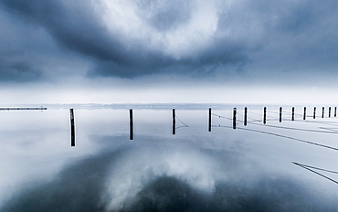 Reflecting UFO cloud over abandoned marina on a foggy winter morning at Lake Starnberg, Bavaria, Germany