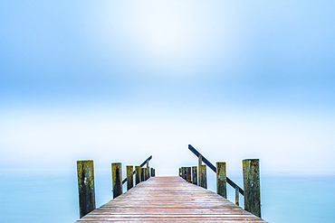 Jetty on Lake Starnberg in autumn morning fog, Garatshausen, Bavaria, Germany