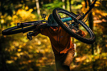 Mountain biker carries his bike through autumn forest, mountain biker, autumn, forest