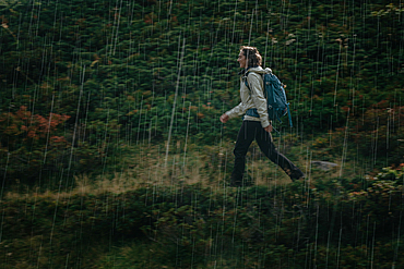 Woman wanders through rain, mountain, Switzerland,