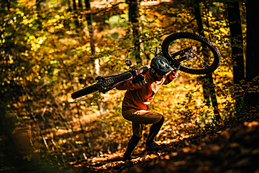 Mountain biker carries his bike through autumn forest, mountain biker, autumn, forest