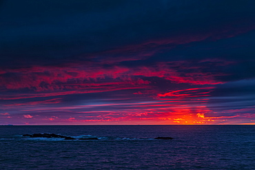 Clouds glowing a bright pink on the horizon over water, Bonavista, Newfoundland, Canada