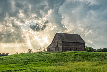 Abandoned barn with storm clouds converging overhead, Nebraska, United States of America