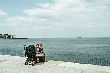 Father and baby boy on a waterfront promenade on the Adriatic Sea, Italy