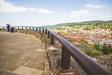 Tourists stand looking out over the coastline and Duino from Duino Castle, Italy