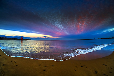 Herd Groyne Lighthouse and dramatic sunset with glowing clouds and tide washing onto beach in the foreground, South Shields, Tyne and Wear, England