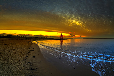 Herd Groyne Lighthouse backlit by a glowing, golden sunset, South Shields, Tyne and Wear, England