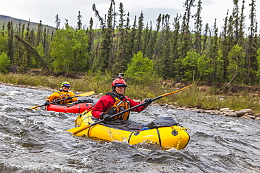 Two women packrafters negotiating a tributary of the Charley River in summertime, Yukon–Charley Rivers National Preserve, Alaska, United States of America