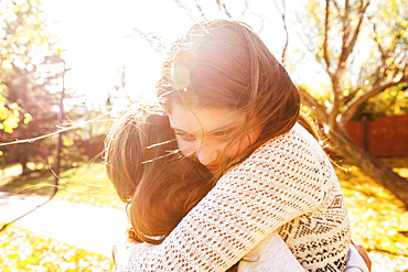 Two sisters hugging each other in a city park on a warm autumn day: Edmonton, Alberta, Canada